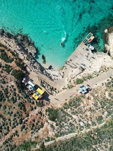 A vertical aerial top view of a bright blue lagoon in Malta