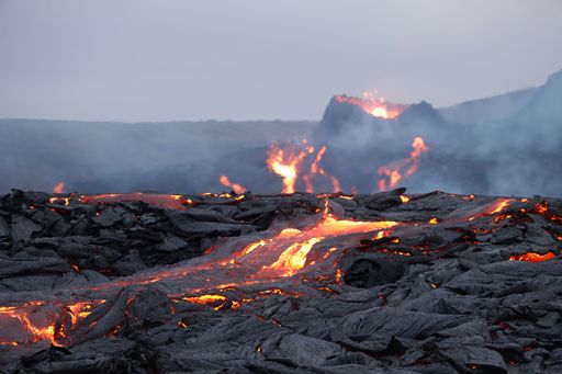 A volcanic eruption with glowing orange lava flow surrounded by a pool of bubbling magma