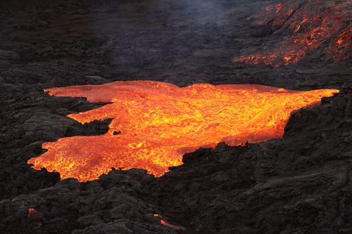A volcanic eruption with glowing orange lava flow surrounded by a pool of bubbling magma