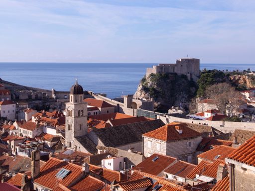 A scenic view of a coastal town, featuring terracotta roofs, chimneys and picturesque houses overlooking the ocean