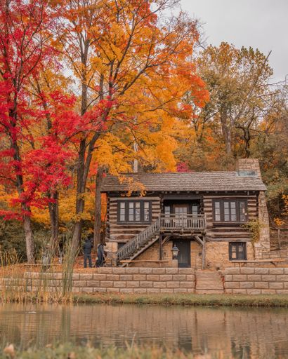 A vertical shot of the colorful tree leaves of the wooden house in the riverbank