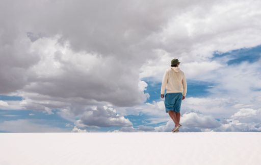 A back view of a stylish man in a snowy field under the cloudy sky