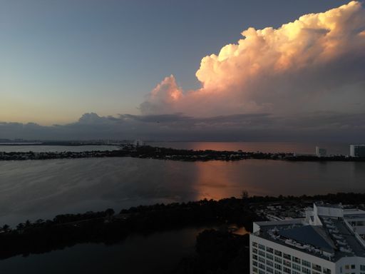 An aerial view of cityscape Miami surrounded by buildings and water during sunset