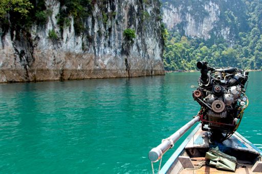 A closeup shot of a boat sailing in the river surrounded by mountains