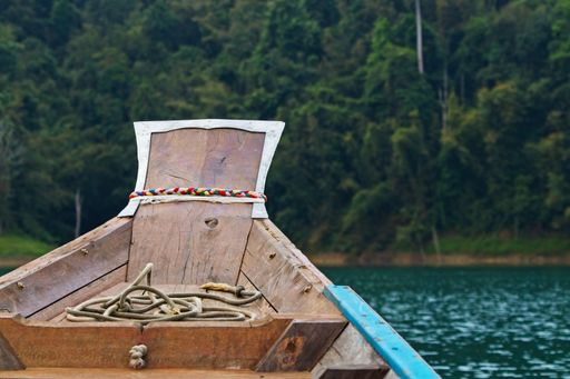 A closeup shot of a boat getting ready to sial in the river surrounded by a forest