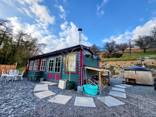 An exterior view of a small cottage with a colorful design in a rural area in daylight