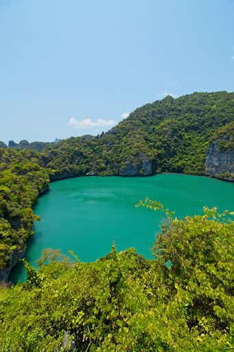 A vertical high angle shot of a beautiful lake surrounded by tree covered mountains in Thailand