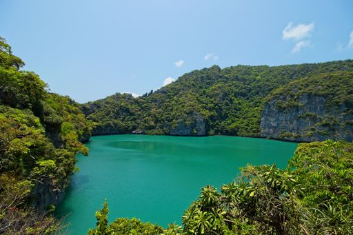 A high angle shot of a lake surrounded by tree covered mountains captured in Thailand
