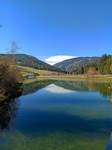 A serene view of a tranquil lake set against the background of mountain hills covered with forests