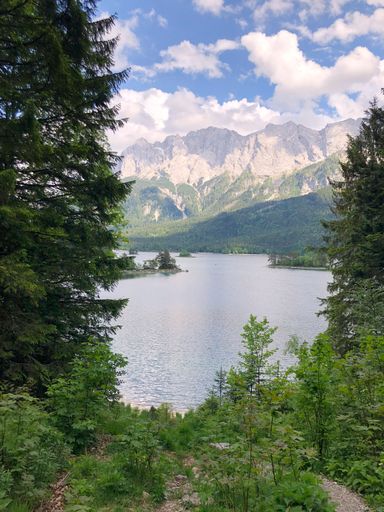 A vertical shot of beautiful scenery of lakeshore with mountains and a cloudy sky in the background