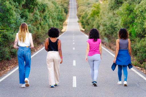 Four women walking side by side along a rural road