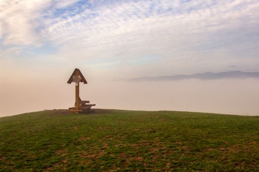 A wooden sign in a green meadow against the backdrop of a cloudy sky. Banska Bystrica, Slovakia.