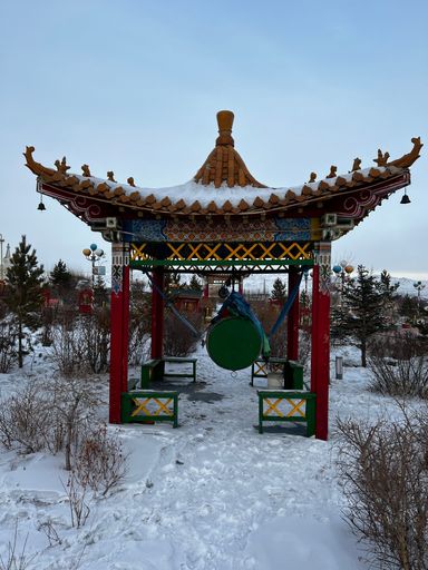 A vertical shot of a traditional Asian pavilion temple with snow on the ground during winter