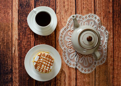 A top view of a delicious cake with caramel topping and a cup of hot tea