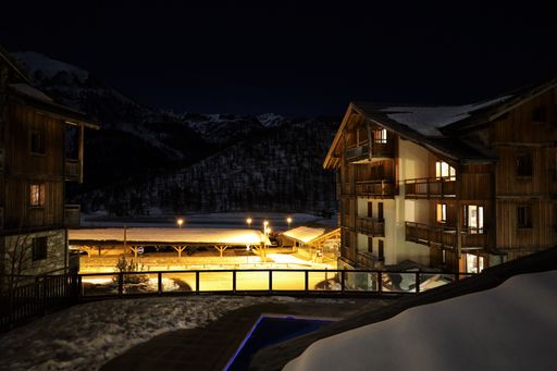 A scenic view of a rustic cabin resort near mountains under a starry night sky in Montgenevre, France