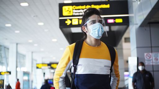 A shallow focus shot of a Caucasian male with a face mask in an airport - concept of the new normal