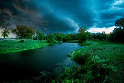 A beautiful river in a meadow with a dramatic cloudy sky in the background, Waco, Texas, United States