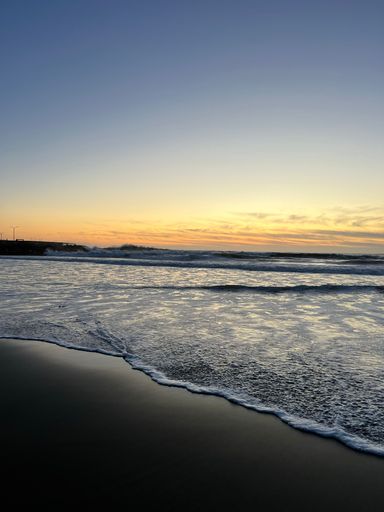 A beautiful vertical view of a sea with small waves under the clear sky during sunrise