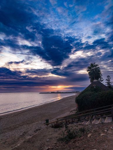 An aerial view of sea with sandy beach during sunset