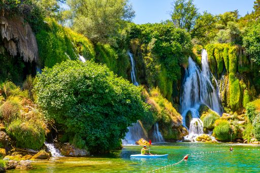 The majestic Kravica Waterfall cascading down amidst lush greenery and trees in Bosnia and Herzegovina