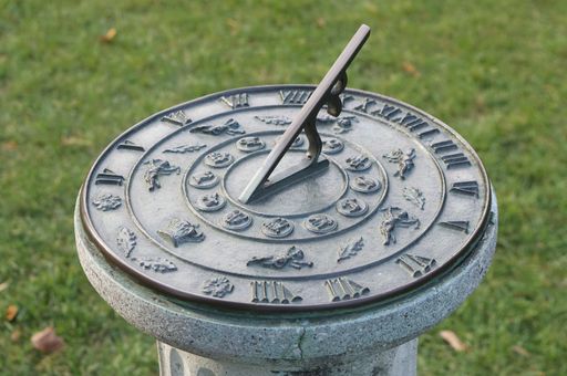 A selective focus shot of an antique sundial in a field