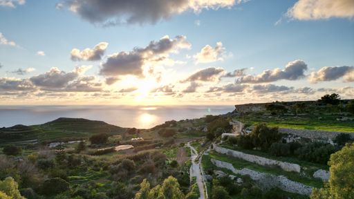 An aerial view of a beautiful coastline at sunset in the horizon