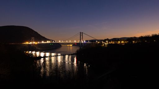 The Bear Mountain bridge lit up at night over the river