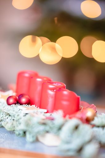 A vertical closeup shot of red Christmas candles with bokeh lights in the backgroun