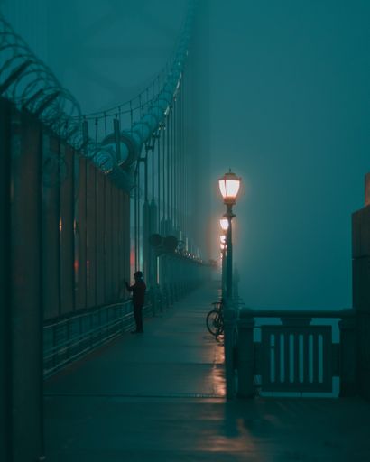A solitary figure standing on a pier on a misty morning, looking out across a body of water