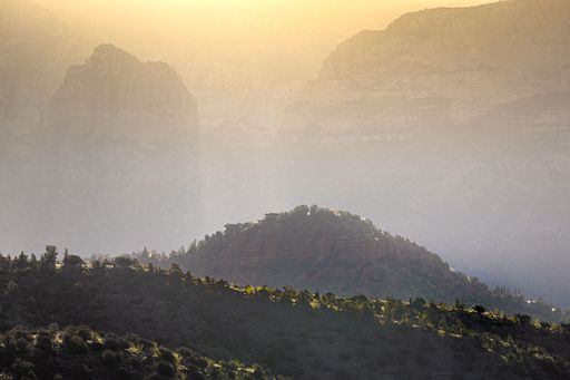 A beautiful shot of the sun shining over rocky mountains on a misty day