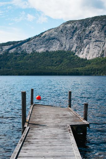 A vertical shot of a wooden door near the lake with high rocky mountains in the background