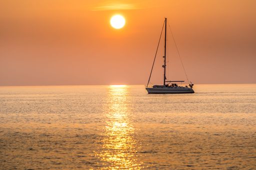 A sailboat silhouetted against a beautiful sunset over the water.