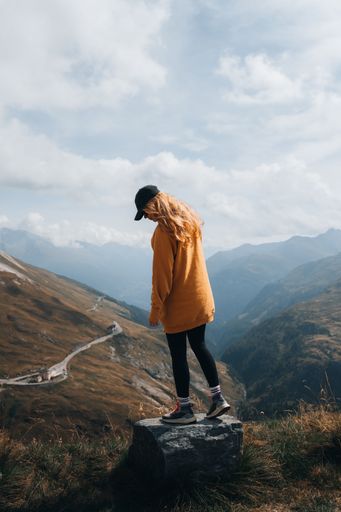 A vertical shot of a blonde female hiker enjoying the view from a mountain near Grossglockner, Austria