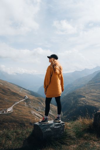 A vertical shot of a blonde female hiker enjoying the view from a mountain near Grossglockner, Austria