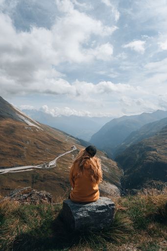 A vertical shot of a blonde female hiker enjoying the view from a mountain near Grossglockner, Austria