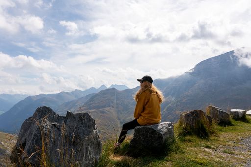 A back view of a blonde female hiker enjoying the view of mountains near Grossglockner, Austria