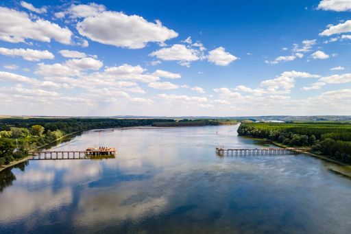 An aerial view of piers on a river with with lush green vegetation on both sides