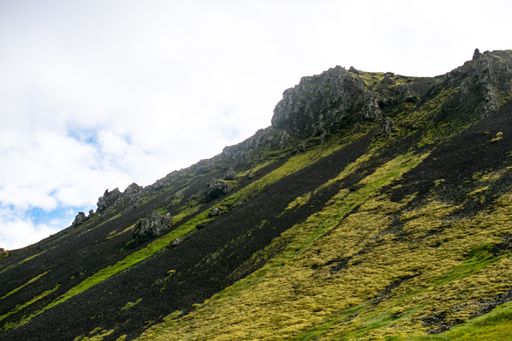 A high green rocky mountain under a cloudy sky