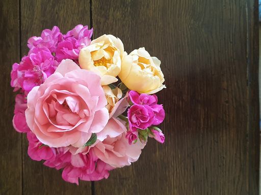A top view of a fresh bouquet of multicolored natural flowers on a wooden table with copy space