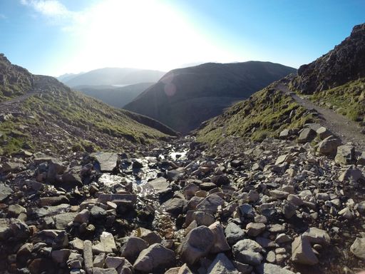 A closeup of a long hiking path between the hills filled in grey stones