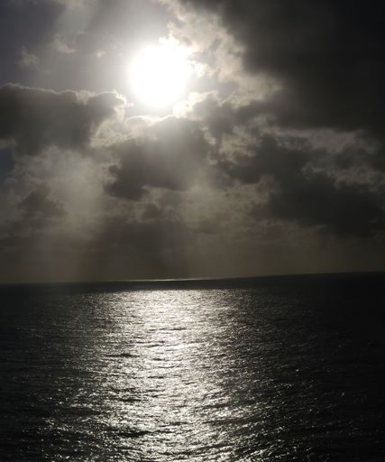 A vertical shot of a bright shining sunny sky over a blue sea