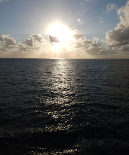 A vertical shot of a bright shining sunny sky over a blue sea