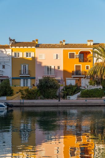 A vertical shot of colorful houses reflected in the water in Port Saplaya during sunset, Valencia Spain