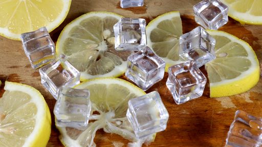 A closeup shot of lemon slices and ice cubes on a wooden surface