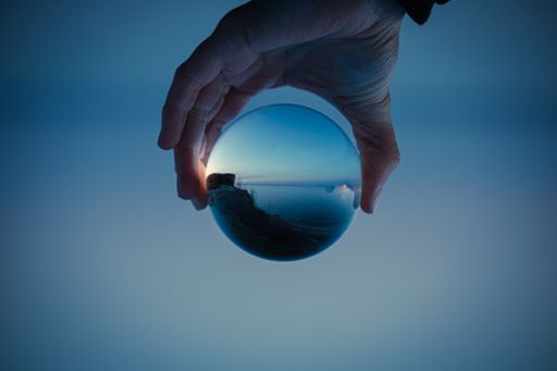 A blue sky with a clear lake in crystal glass ball holding in hand
