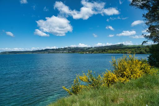 A stunning view of Lake Taupo, New Zealand, showing the tranquil blue waters surrounded by lush green hills and forests
