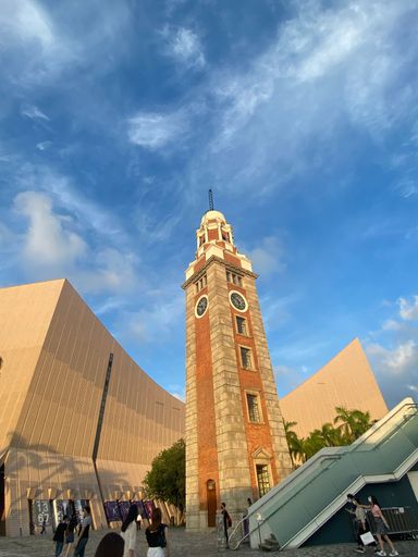 A low-angle shot of the clock tower in Hong Kong against the sunny blue sky