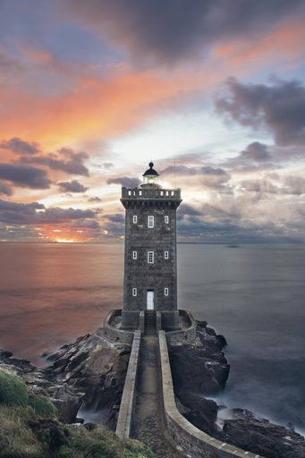 French lighthouse facing a sunset in portrait format