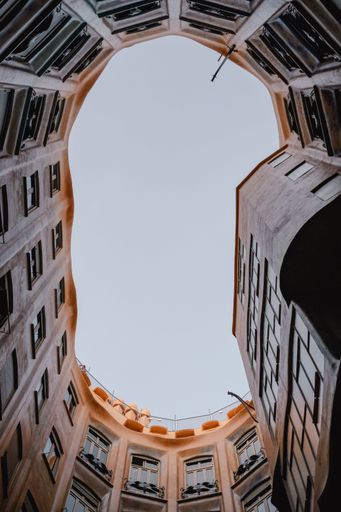 A vertical low angle shot of a blue sky through a rounded building in Barcelona, Spain