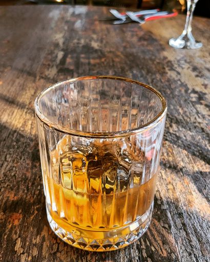 A vertical of the alcohol with ice in a glass put on the wooden table surface